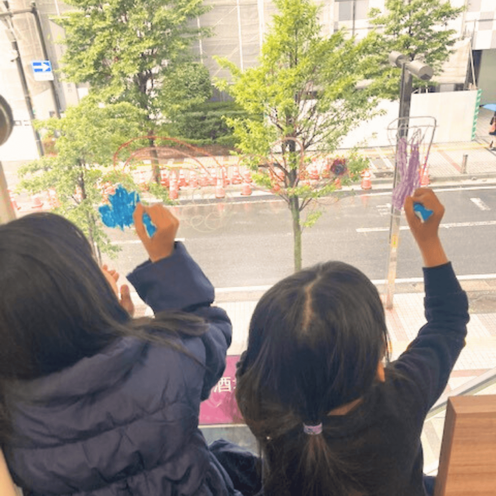 キッズスペースでkitpasで窓に絵を描く子どもの写真1