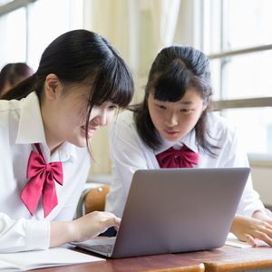 ノートパソコンを操作する2人の女子高校生