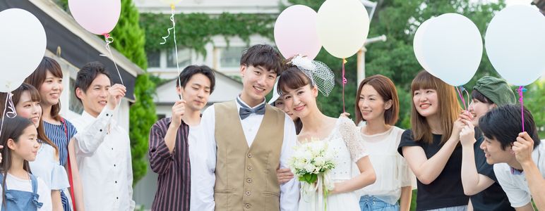 新郎新婦と、風船を持つ結婚式のゲストたち