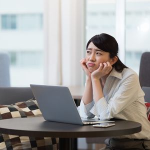 ノートPCを開き、困った顔をする女性