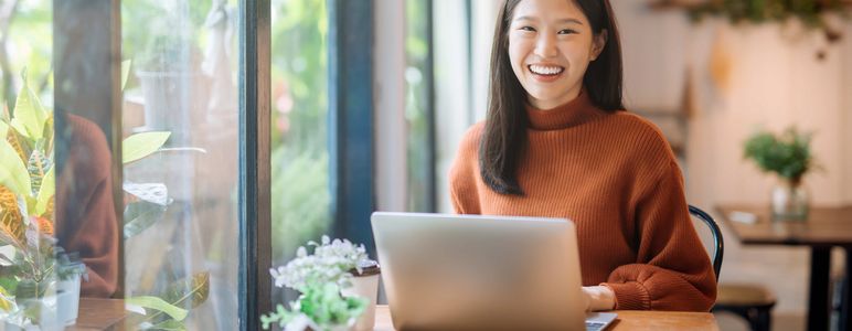 カフェでノートパソコンを開いて仕事する女性