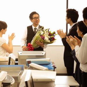 退職祝いに花束を渡された男性